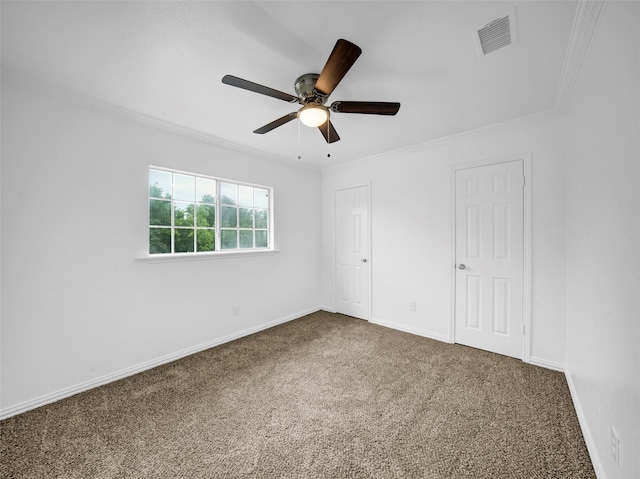 unfurnished bedroom featuring carpet flooring, a ceiling fan, visible vents, baseboards, and ornamental molding