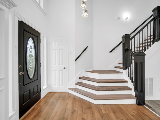 foyer with baseboards, stairway, visible vents, and wood finished floors
