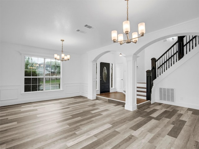 entrance foyer featuring a decorative wall, a notable chandelier, arched walkways, and visible vents
