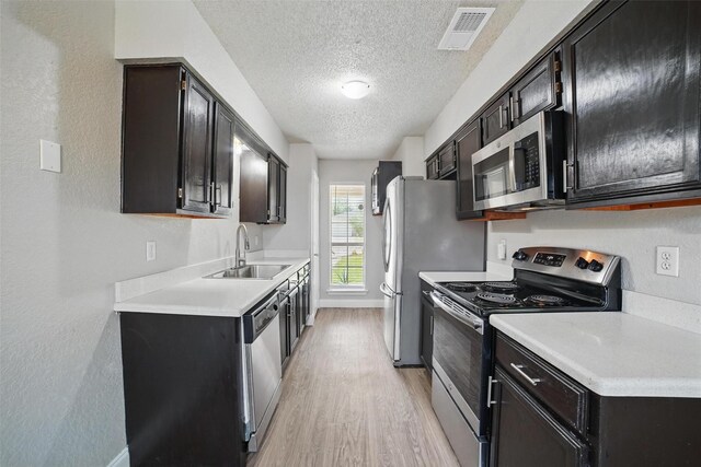 704 Loganwood Dr, Royse City, TX 75189 - kitchen with stainless steel appliances, a sink, a textured ceiling, light wood finished floors, and light countertops