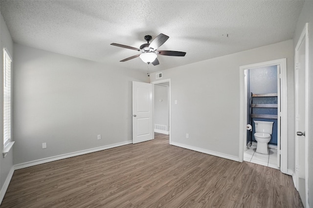 704 Loganwood Dr, Royse City, TX 75189 - unfurnished bedroom featuring wood finished floors, a textured ceiling, connected bathroom, baseboards, and a ceiling fan