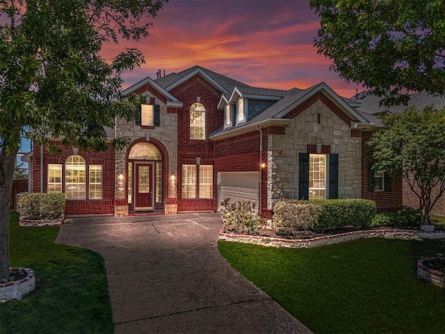 view of front of house with concrete driveway, stone siding, a front lawn, an attached garage, and brick siding