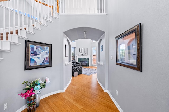 hall featuring baseboards, wood finished floors, and arched walkways
