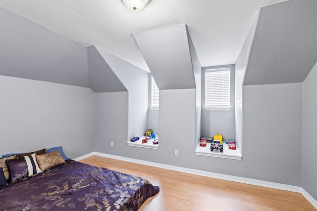 bedroom with wood finished floors, baseboards, and lofted ceiling