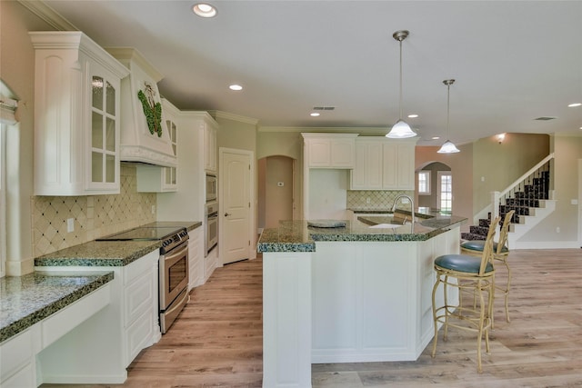 kitchen featuring a sink, stainless steel appliances, tasteful backsplash, and arched walkways