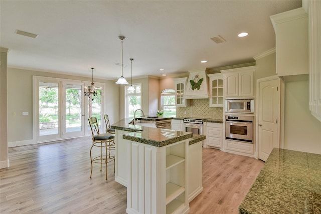 kitchen featuring crown molding, stainless steel appliances, open shelves, and a breakfast bar area