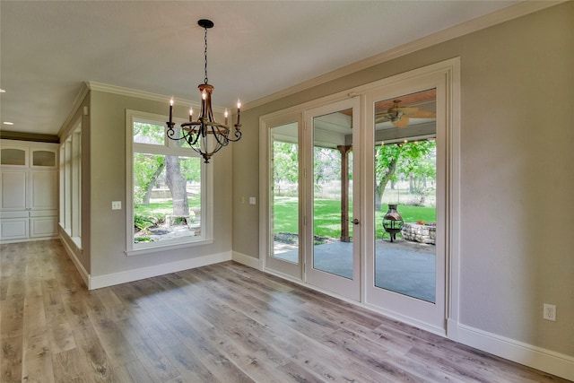 doorway featuring crown molding, light wood-style floors, a chandelier, and baseboards