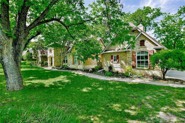 view of front of home featuring a front lawn, brick siding, and a chimney