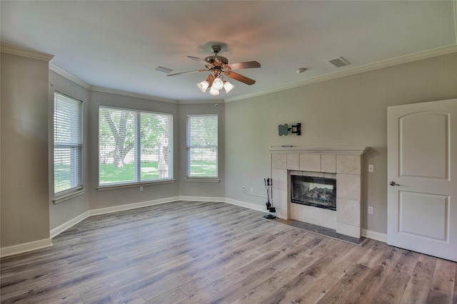 unfurnished living room with wood finished floors, visible vents, crown molding, a ceiling fan, and a tile fireplace