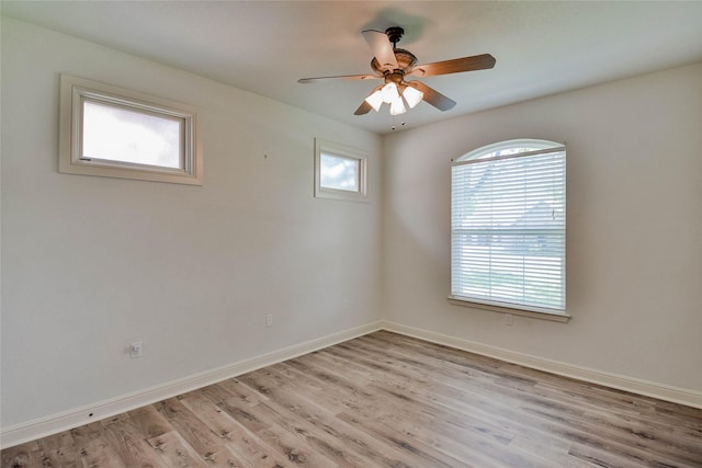 empty room featuring a wealth of natural light, baseboards, a ceiling fan, and light wood-type flooring