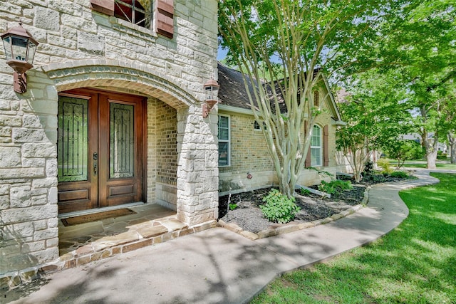 view of exterior entry featuring stone siding and brick siding