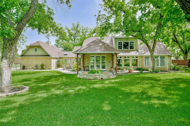 back of property featuring a shingled roof, brick siding, and a lawn