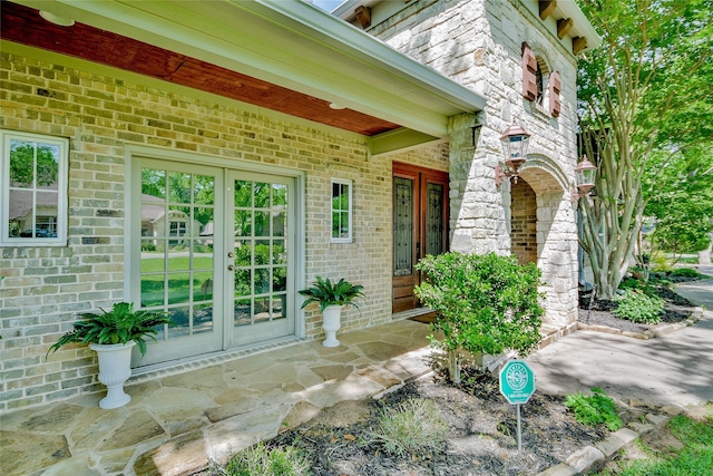 doorway to property featuring covered porch, french doors, and brick siding