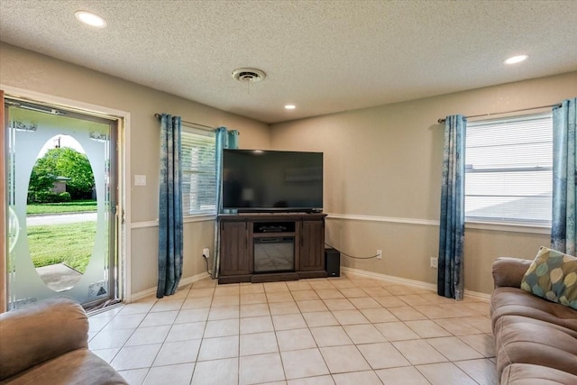 living area with light tile patterned flooring, a textured ceiling, visible vents, and recessed lighting