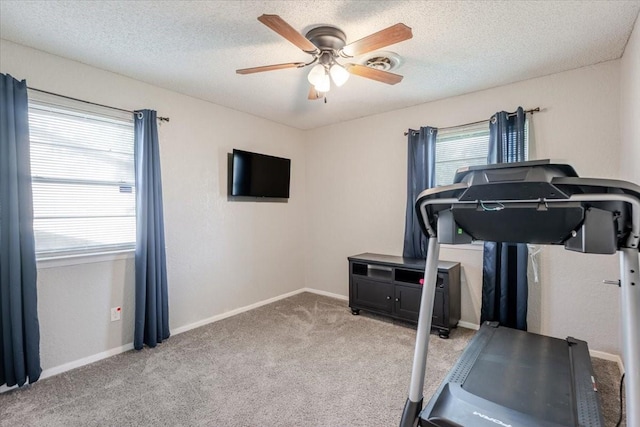 workout room featuring a ceiling fan, carpet floors, a textured ceiling, and plenty of natural light