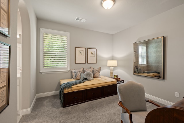 bedroom with arched walkways, baseboards, visible vents, and carpet