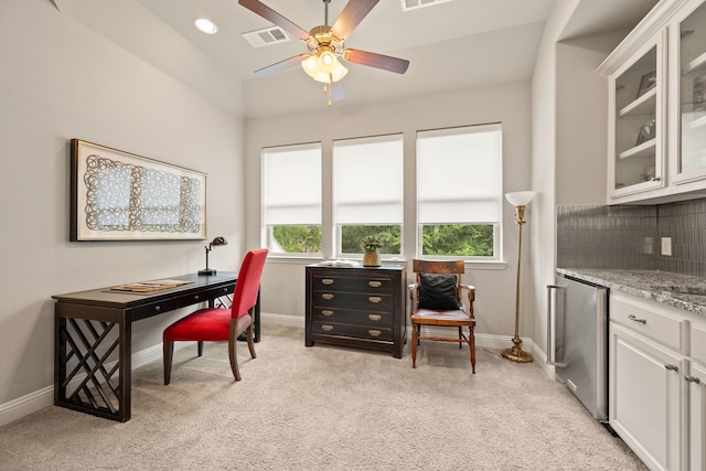 office area featuring a ceiling fan, visible vents, baseboards, light colored carpet, and lofted ceiling