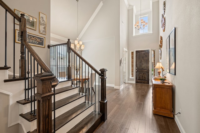 entryway featuring baseboards, dark wood-style floors, an inviting chandelier, and a towering ceiling