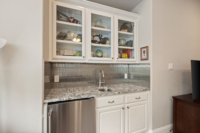 bar featuring baseboards, refrigerator, a sink, wet bar, and tasteful backsplash