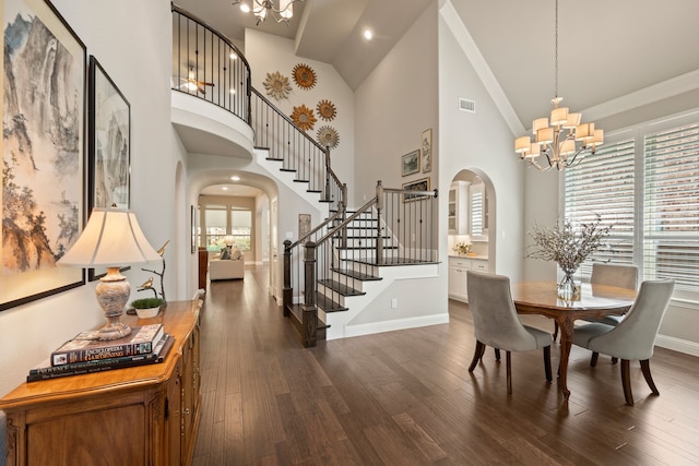 dining area featuring an inviting chandelier, visible vents, dark wood-style flooring, arched walkways, and stairs