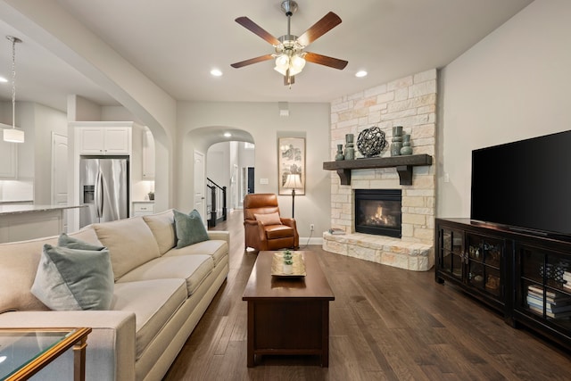 living area featuring a fireplace, dark wood-type flooring, ceiling fan, arched walkways, and recessed lighting