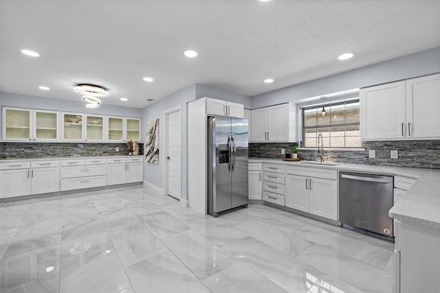 kitchen with white cabinets, appliances with stainless steel finishes, decorative backsplash, and a sink