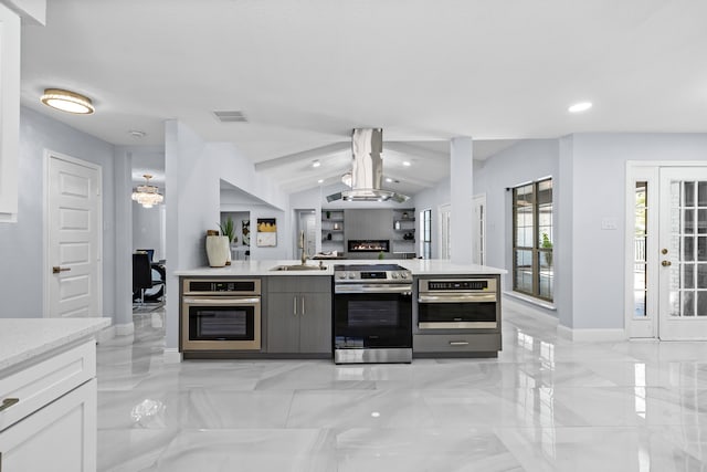kitchen featuring visible vents, a sink, island exhaust hood, open floor plan, and appliances with stainless steel finishes