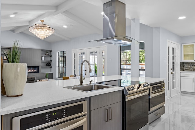 kitchen with a sink, wall chimney range hood, french doors, marble finish floor, and recessed lighting