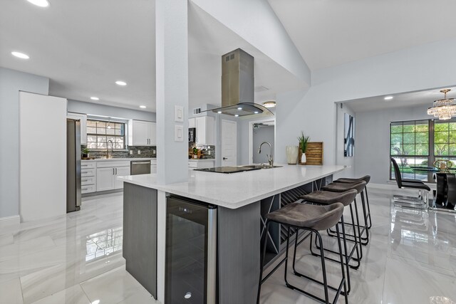 kitchen with a breakfast bar area, island exhaust hood, white cabinets, appliances with stainless steel finishes, and wine cooler