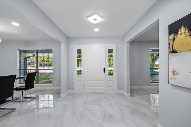 entrance foyer with a wealth of natural light, baseboards, and marble finish floor