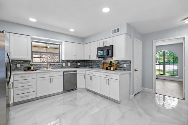 kitchen with a sink, white cabinets, visible vents, appliances with stainless steel finishes, and tasteful backsplash