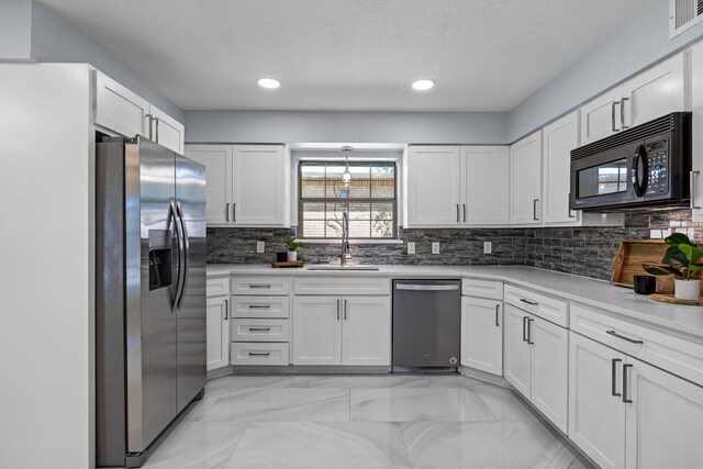 kitchen featuring a sink, white cabinetry, tasteful backsplash, appliances with stainless steel finishes, and marble finish floor