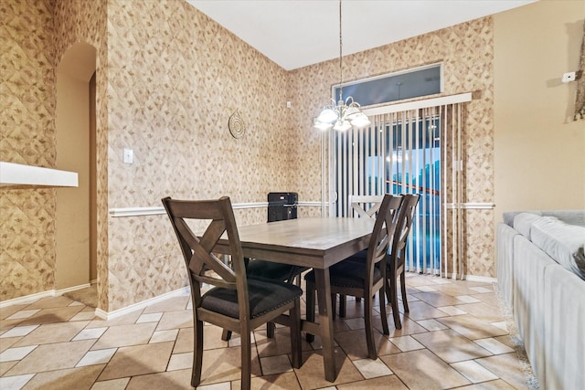 dining room featuring a notable chandelier, baseboards, and wallpapered walls