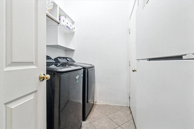 laundry area featuring washing machine and clothes dryer, baseboards, laundry area, and light tile patterned floors