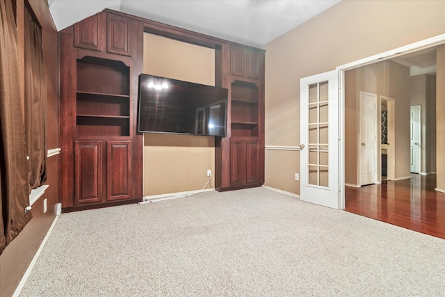 unfurnished living room featuring carpet flooring, french doors, and baseboards