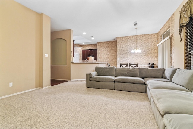 living area featuring carpet, baseboards, wallpapered walls, and a notable chandelier