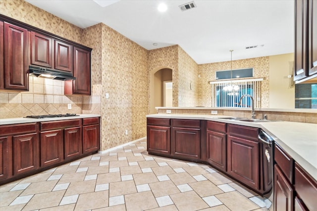kitchen featuring a sink, reddish brown cabinets, visible vents, under cabinet range hood, and light countertops