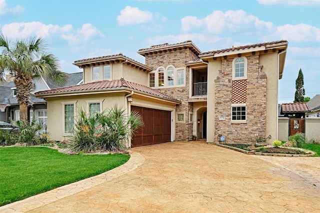 mediterranean / spanish house featuring a balcony, decorative driveway, stucco siding, stone siding, and a front lawn