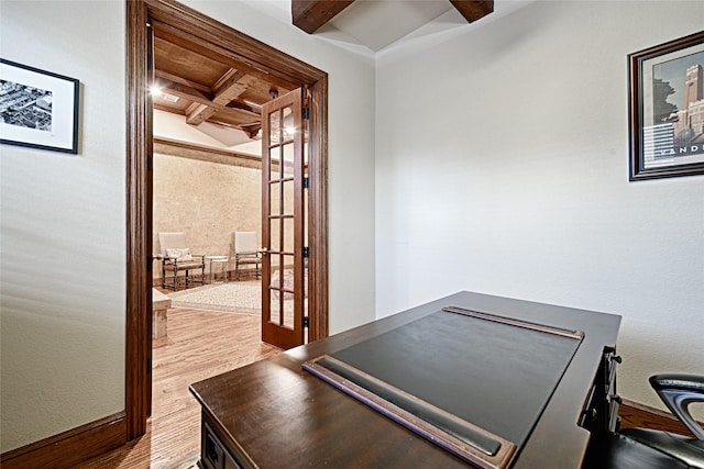 unfurnished office featuring coffered ceiling, beamed ceiling, french doors, and wood finished floors