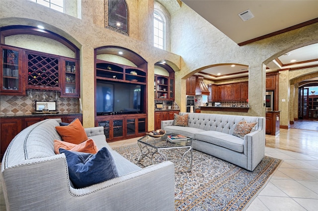 living room featuring light tile patterned floors, a high ceiling, visible vents, arched walkways, and built in shelves
