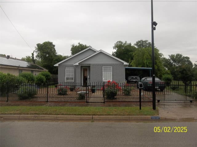 bungalow-style house featuring a fenced front yard and a carport