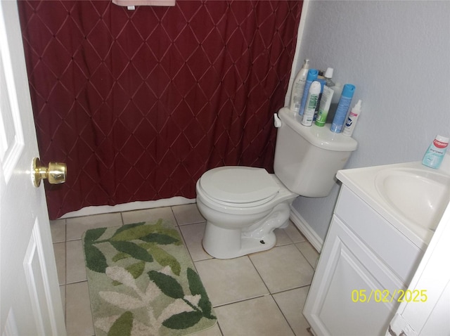 half bathroom with toilet, tile patterned flooring, vanity, and baseboards