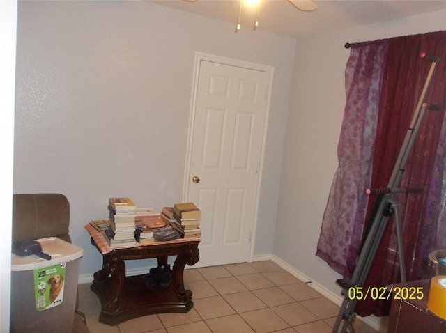 interior space featuring light tile patterned floors, baseboards, and ceiling fan