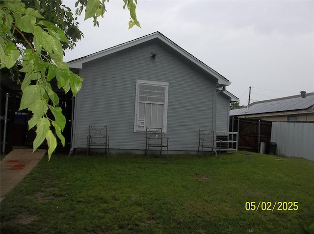 rear view of house featuring fence and a lawn
