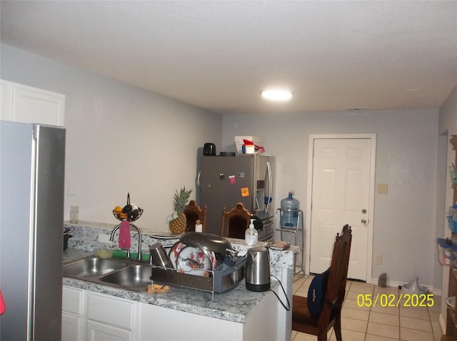 kitchen featuring freestanding refrigerator, light tile patterned flooring, stainless steel fridge with ice dispenser, light countertops, and white cabinets