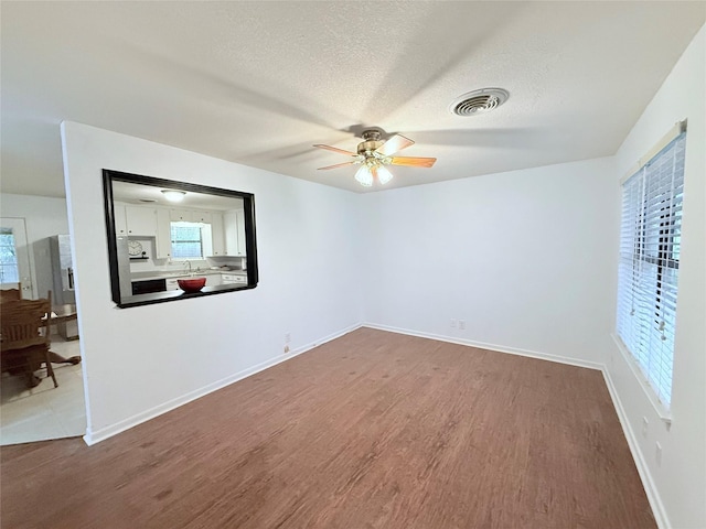 152 N Imperial Dr, Denison, TX 75020 - empty room featuring wood finished floors, a ceiling fan, plenty of natural light, and a textured ceiling