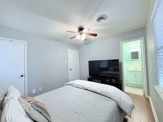 152 N Imperial Dr, Denison, TX 75020 - bedroom featuring light wood-style flooring, a textured ceiling, ensuite bath, and a ceiling fan