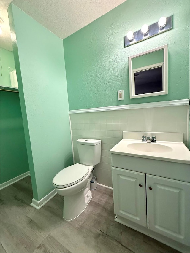 152 N Imperial Dr, Denison, TX 75020 - half bath with wood finished floors, vanity, a textured ceiling, a wainscoted wall, and tile walls