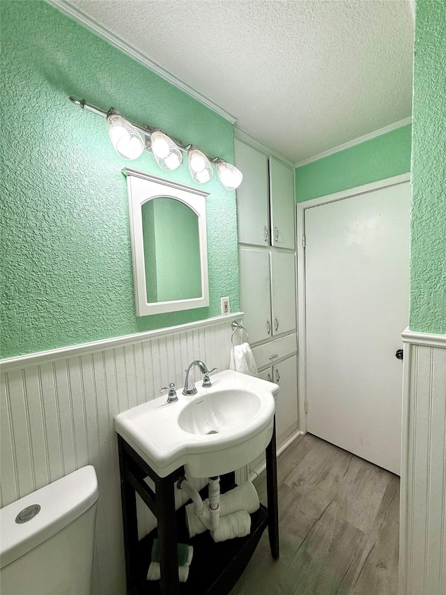 152 N Imperial Dr, Denison, TX 75020 - bathroom with wood finished floors, a textured ceiling, a wainscoted wall, and crown molding