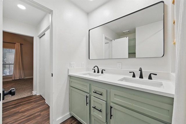 bathroom featuring baseboards, double vanity, a sink, and wood finished floors